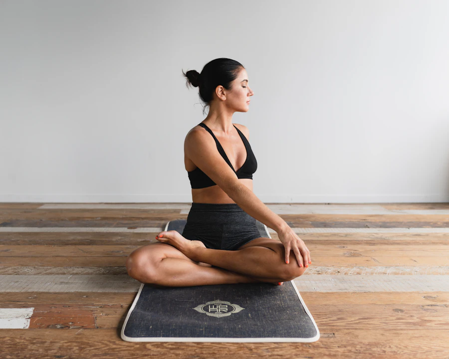 Une pratiquante assise sur son tapis dans une posture de yoga